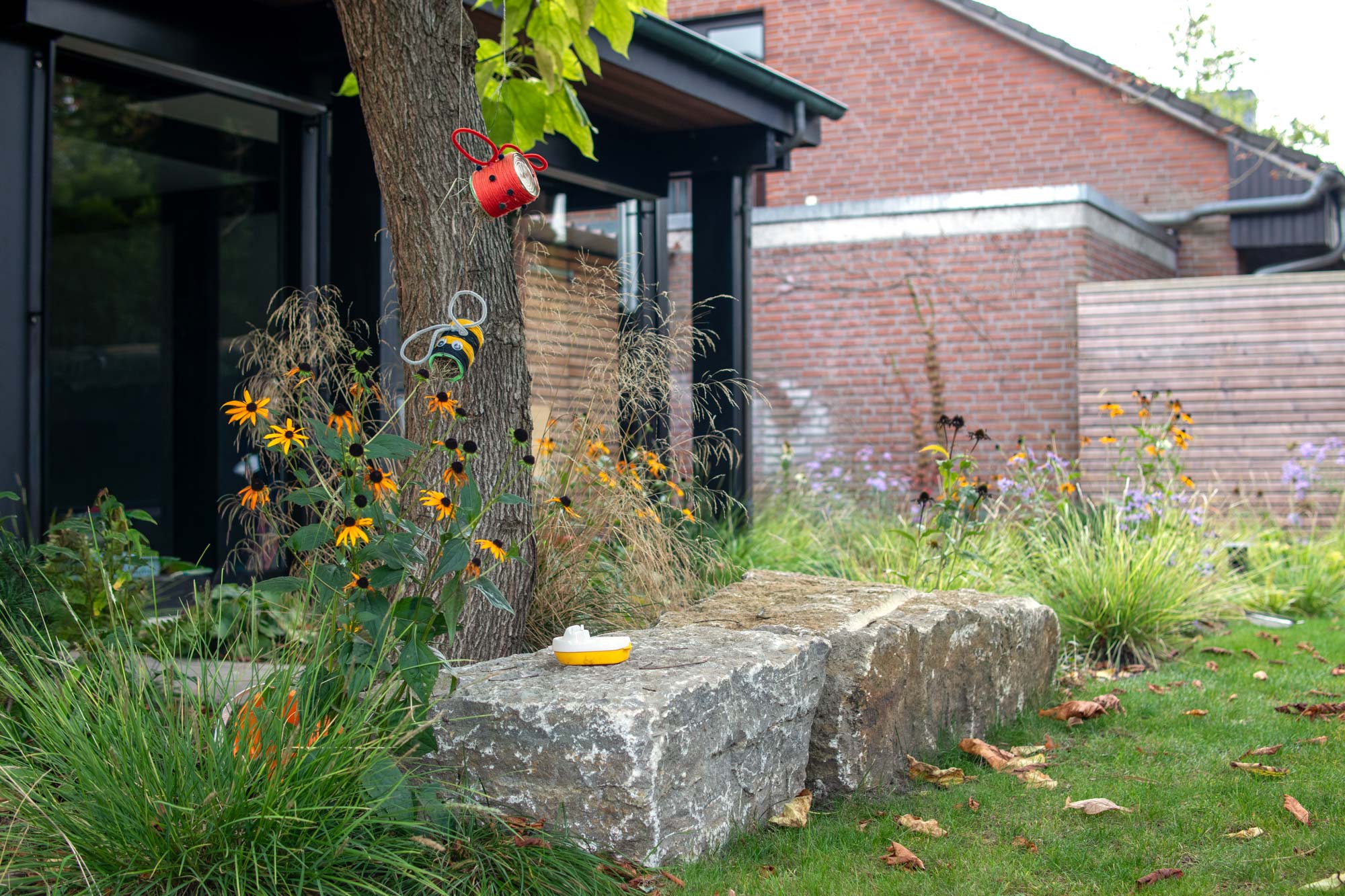 Homann-Landschaften-Garten--und-Landschaftsarchitektur-035-kinderspiel-muschelkalk-sitzblock-unterpflanzung-deschampsia-sesleria-aster-planting-design