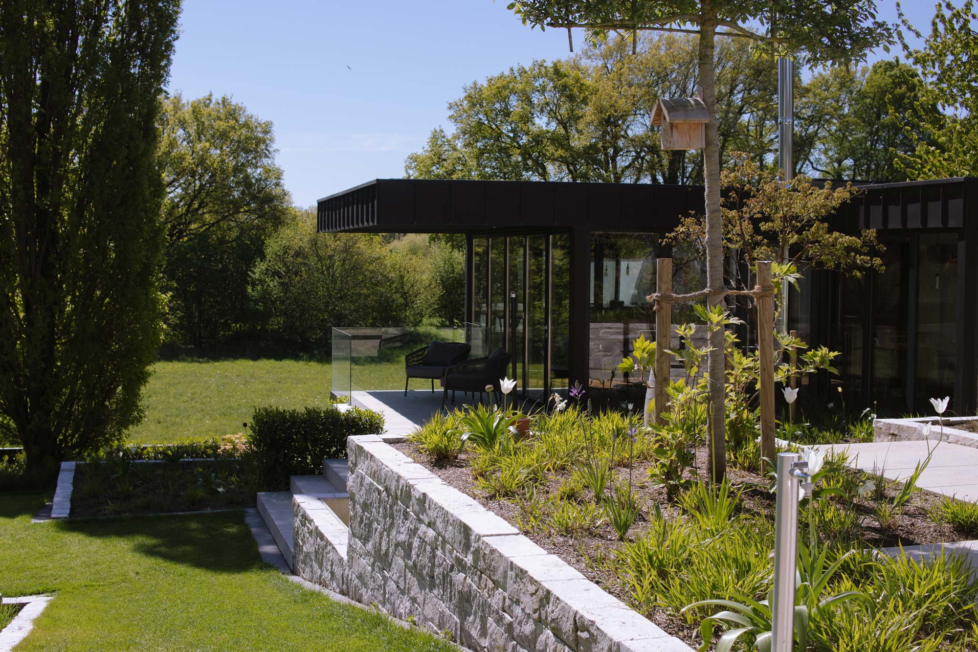 Homann Landschaften Garten  und Landschaftsarchitektur hanggarten natursteinmauer travertin ausblick garten freisitz bepflanzung modern tulipa